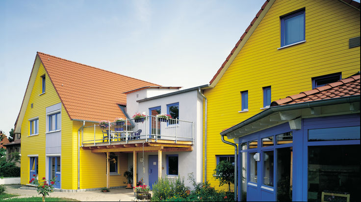 Haeuserverbund mit gelber Fassade und blauen Fenstern