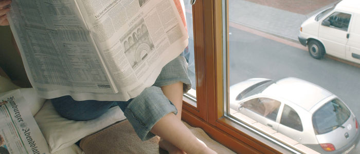 Zeitung lesen am Fenster zur Straße